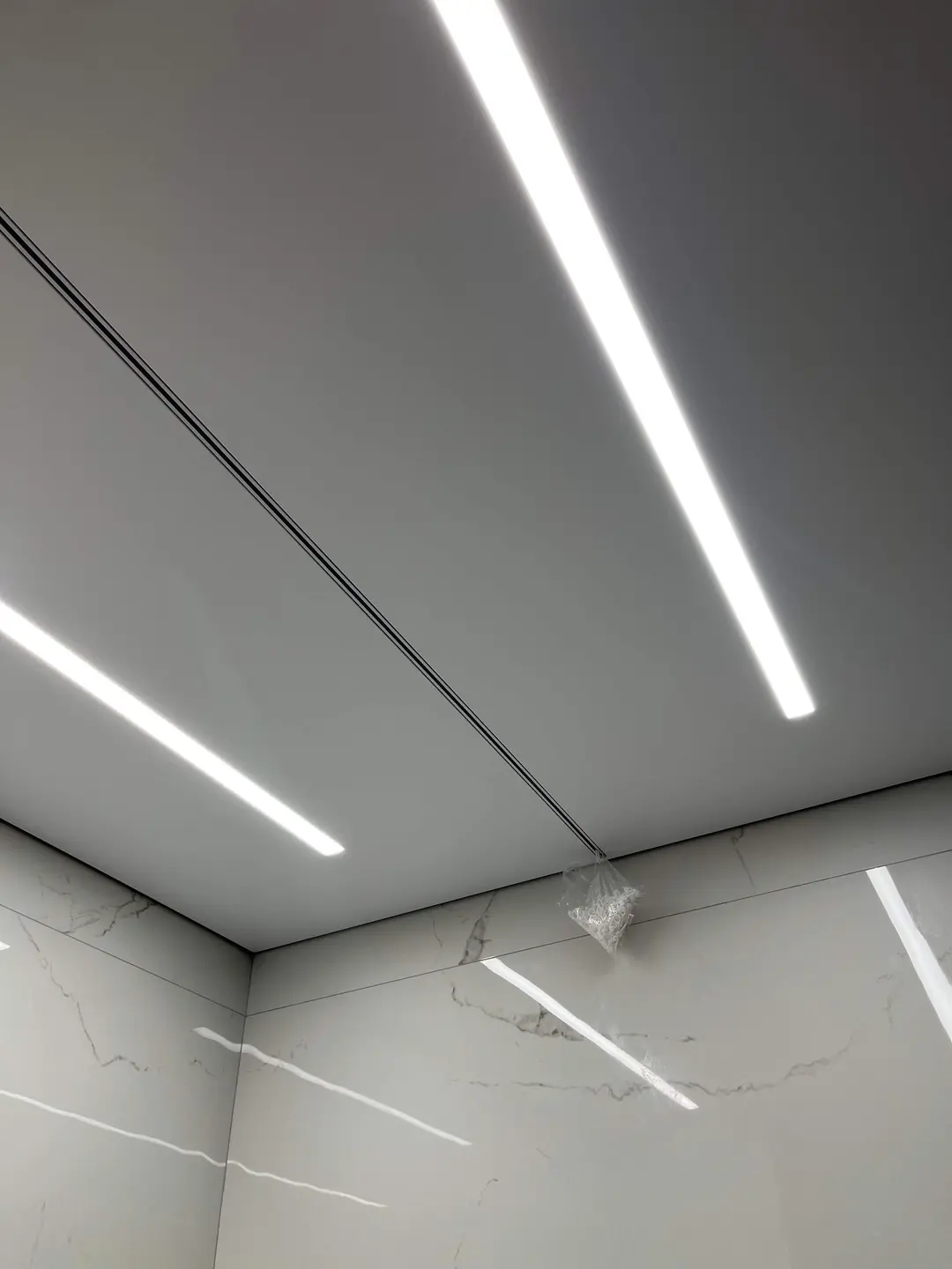 Cortinero empotrado y líneas de luz en un techo tensado – obra realizada